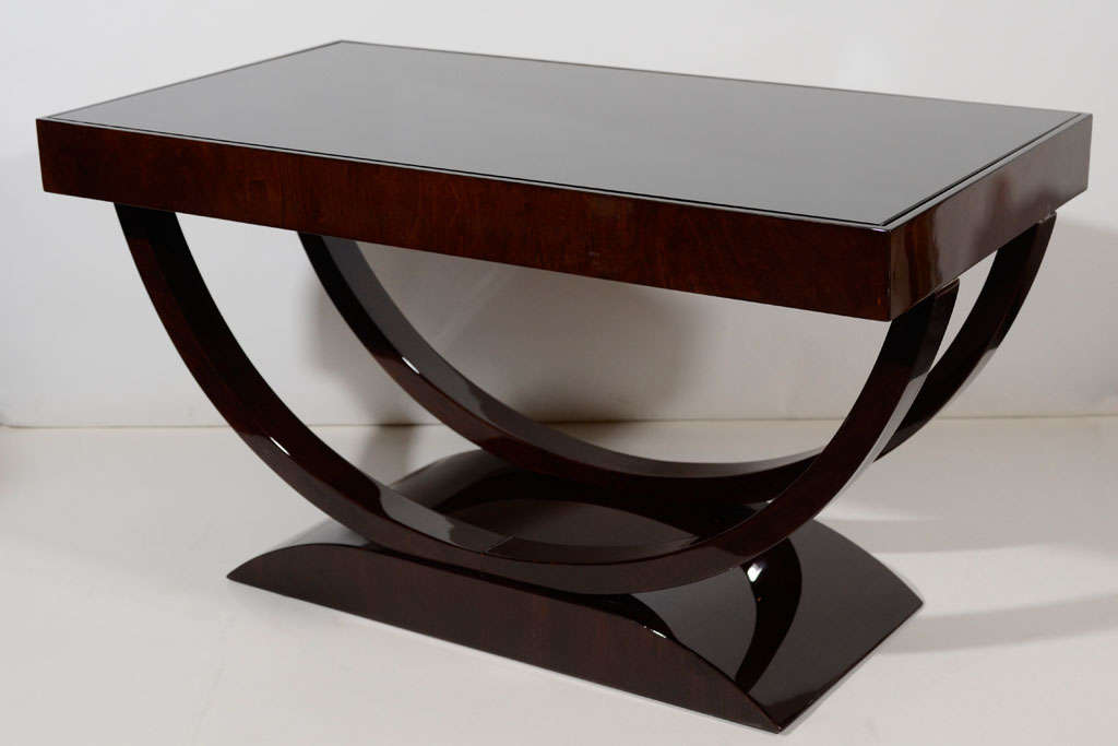 Art Deco coffee or cocktail table with streamline design in walnut wood with black lacquered accents, and with vitrolite (black glass) top. Table has rectangular top and stylized base with double 
