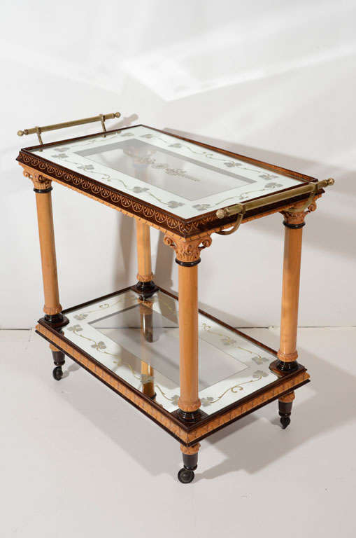 Outstanding Art Deco/neoclassical bar cart with two tier design. The serving cart features the original mirrored and glass tops with églomisé (reverse etched) floral designs. The bar cart is made of sycamore and mahogany woods with ebony details.