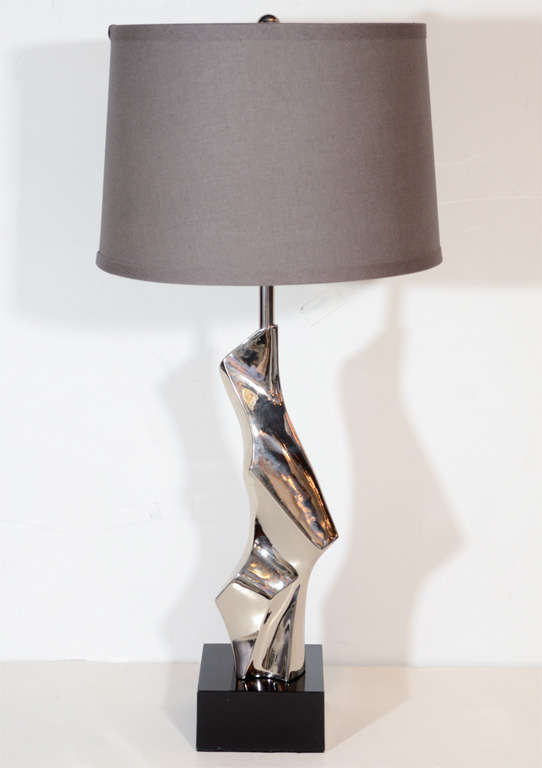 This chic lamp features  a stylized sculptural /Cubist design form in polished nickle resting on a black enamel base. Newly rewired with custom shade.Would also be great on a desk or console.