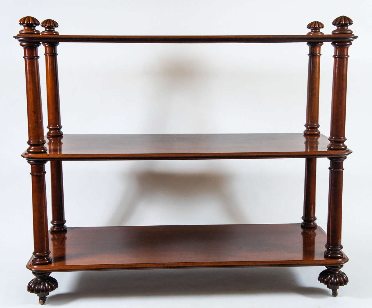 Exquisite English George IV period mahogany three-tier étagère form trolley server of large scale having gadroon relief carved knob form finials atop double Tuscan form colonette side supports on large dramatic gadroon relief-carved bottom