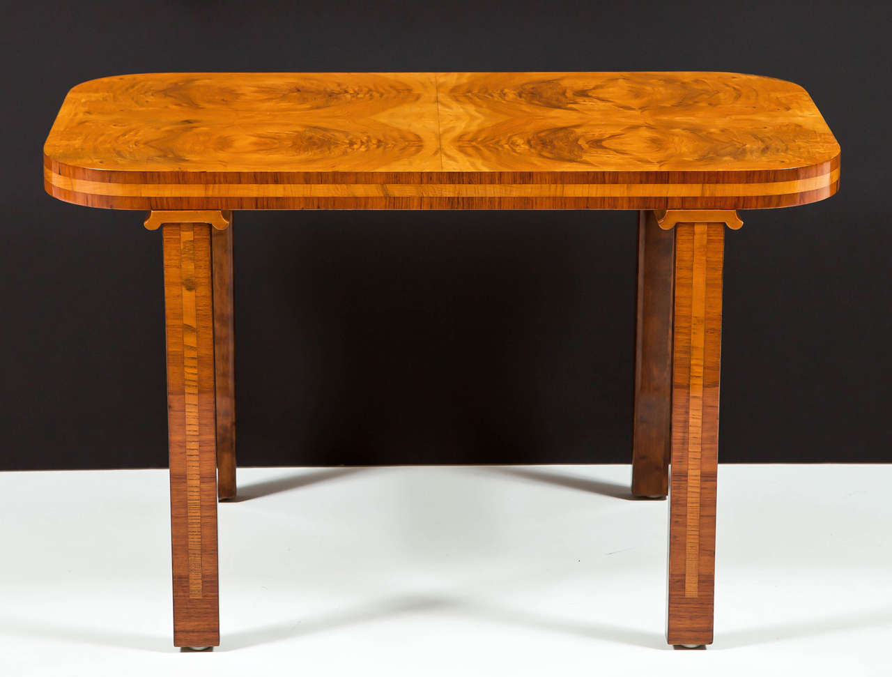 A Swedish modern burl elm, walnut and fruitwood table, circa 1930s, the rectangular top with slightly rounded corners above a banded frieze, raised on rectangular banded legs headed with stylized capitals.