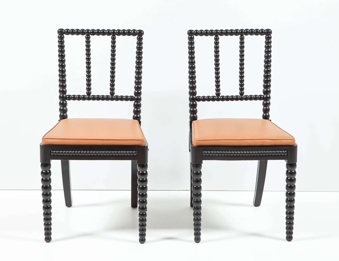 A good set of eight Danish ebonized spool chairs, Third Quarter 19th Century, each with  a rectangular spool turned backrest, drop-in upholstered seats raised on tapered spool tuned legs.