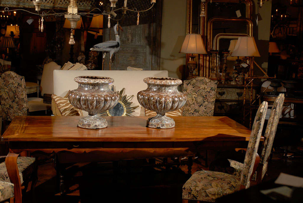 A pair of large French Alfred Corneau à Charleville marbleized iron urns from the mid 19th century. This pair of urns were made by Alfred Corneau in the 1850s. Each featuring a bulbous shape, the iron urns are topped with a large lip and decorated