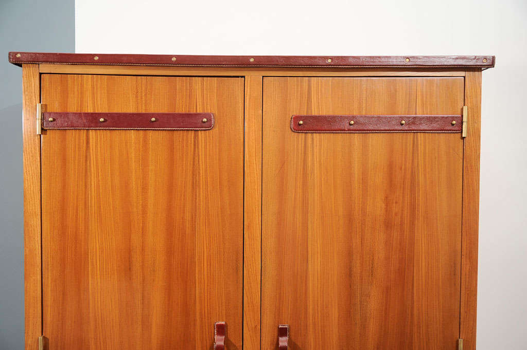 Two-door walnut armoire with leather top and details<br />
by Jacques Adnet (1901 –1984)<br />
Bronze sabot, mahogany interior.