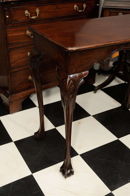 A mid-19th century mahogany side table with a shaped apron and scalloped frieze centered by a shell and palerae, raised on cabriole legs with elongated tendrils on ball and claw feet.