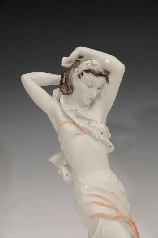 This porcelain figurine by Rosenthal is hand sculpted and hand painted. It depicts a spirited cabaret dancer with a 1940s hairstyle dressed in a costume typical to 1940s cabaret and screen. Signed L.G.F. attributed to Lore Friedrich-Gronau a