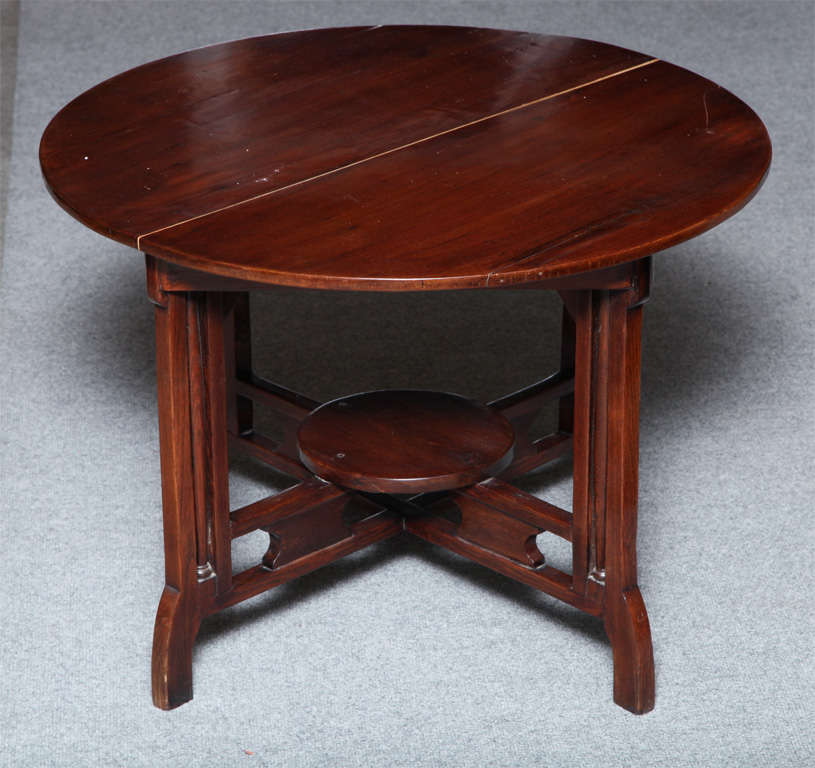 This unusual round coffee table is made of varnished elm and was carved in Shanghai in an uncommon Art Deco style. The circular top is made of two elm planks and varnished with a warm red lacquer. The table is raised on four legs with delicate