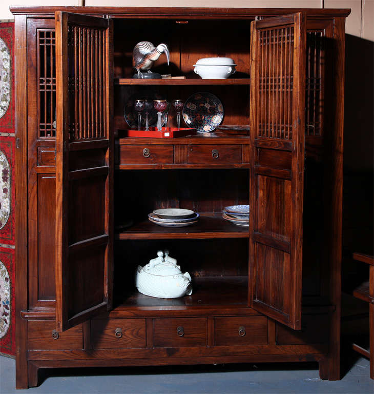 This large and unusual Anglo-Chinese, turn-of-the century elmwood armoire displays accordion openwork doors with two drawers within and five drawers below. The well grained refinished wood ensures an excellent condition to this display cabinet,