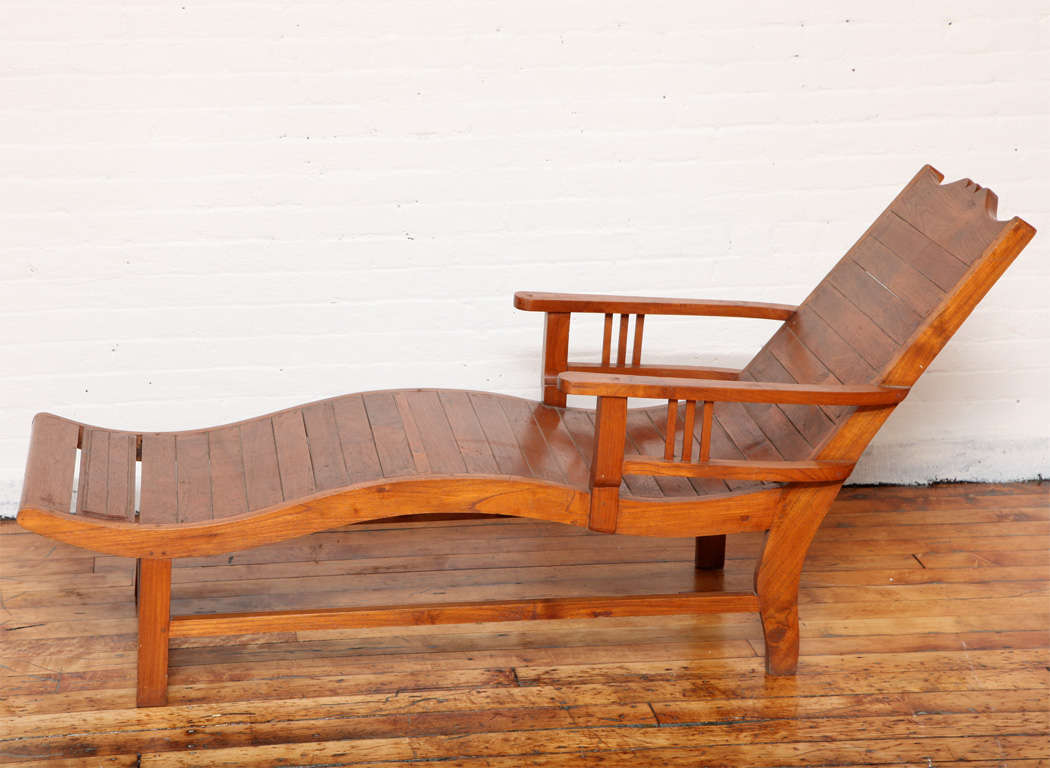 A 1940s Dutch Colonial style teak lounge chair from Java with wavy seat and slanted back. This lovely vintage Dutch Colonial style lounge chair was made of teak on the island of Java in the mid-20th century. The teak planks are magnificently
