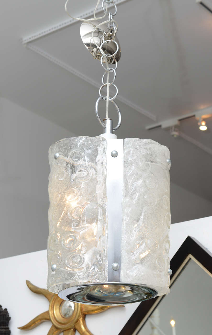 Chrome chandelier featuring 3 demi lune textured glass panels, lit from within. Chrome bottom has an additional downward facing light.  Adjustable pendant chain gives many height choices.