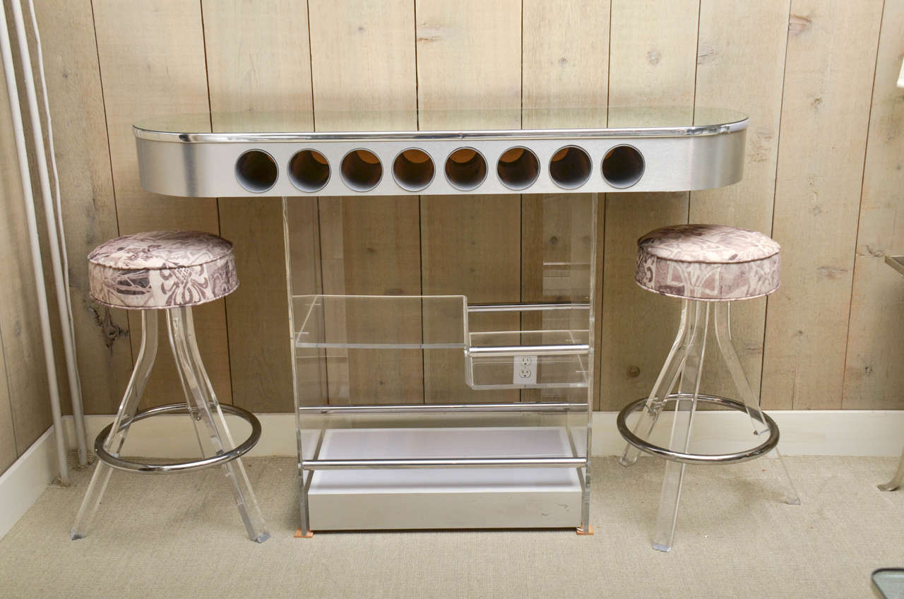 Beautiful vintage oval Lucite bar with mirrored top and chrome trim. The bar comes with two bar stools.