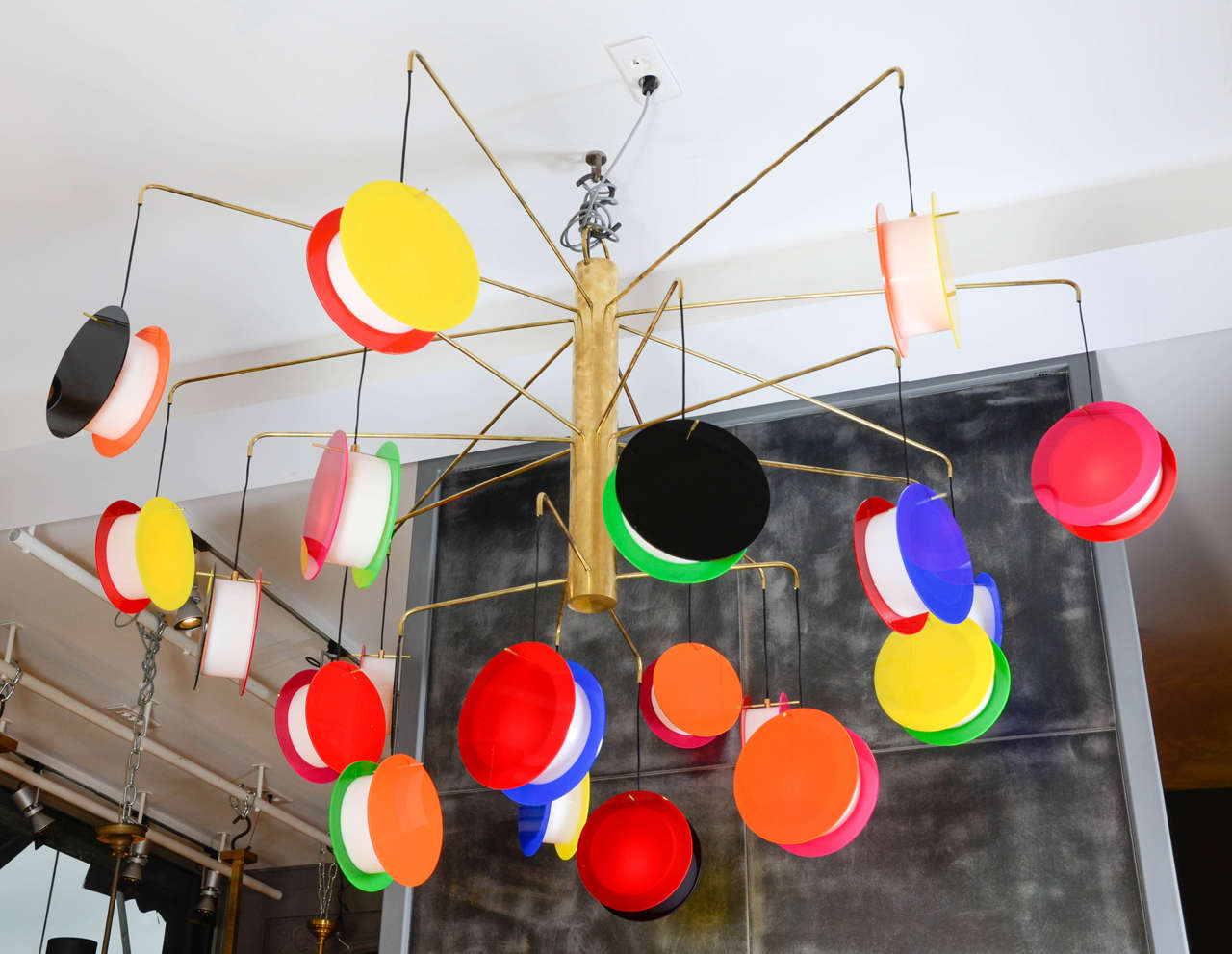 Unique chandelier by Adriano Albini made of a brass structure and arms on which hang 20 colored module.
Each module is made of a white plexiglass round between two colored circles.
Every color is randomly put among the arms.
