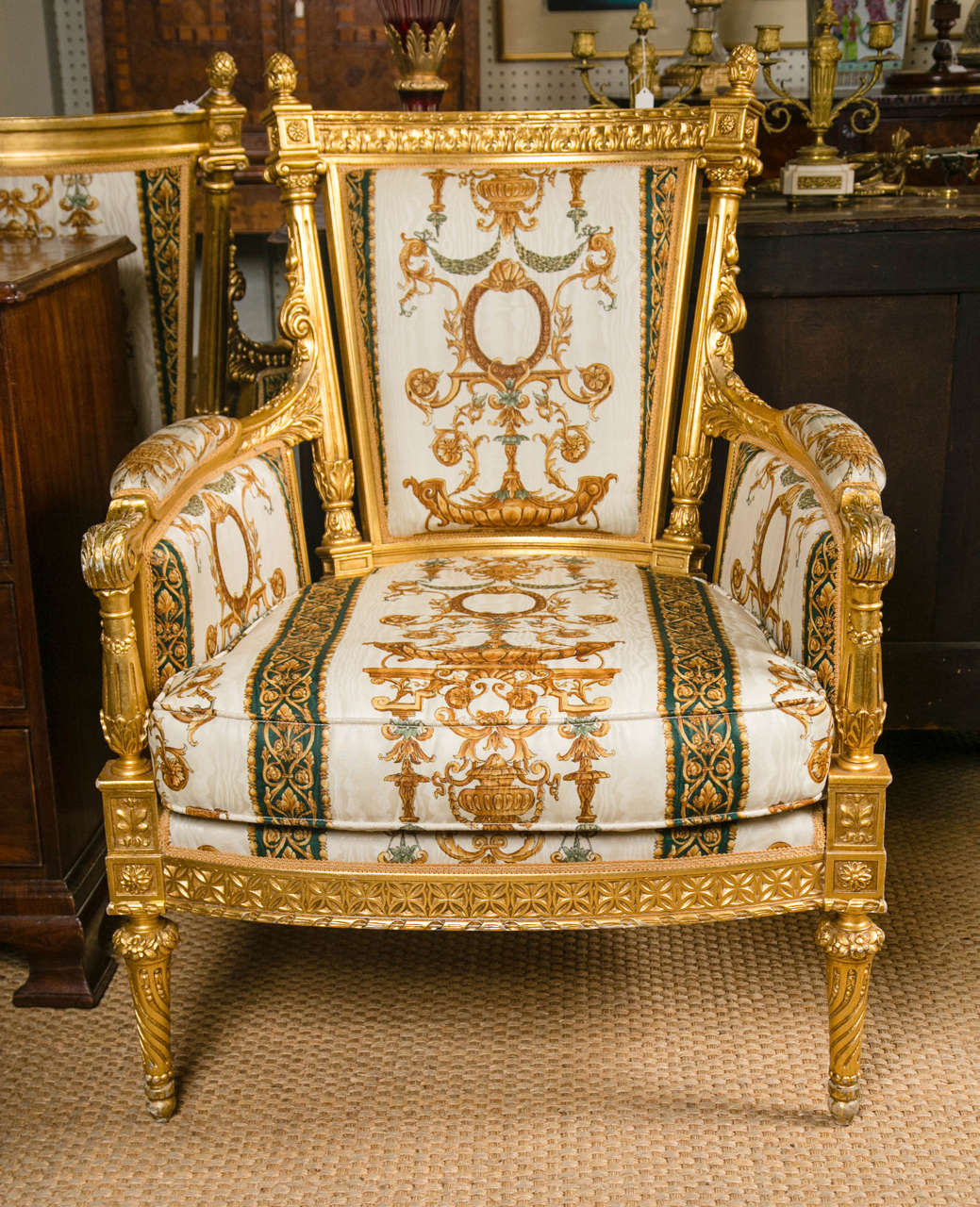 This pair of gilt wood bergeres are extra wide and deep. They are from the Versace Collection and are upholstered in his  bold pattern fabric.  Acorn finials across the top rail which is  carved with acanthus leaves. Separate from the back, fluted