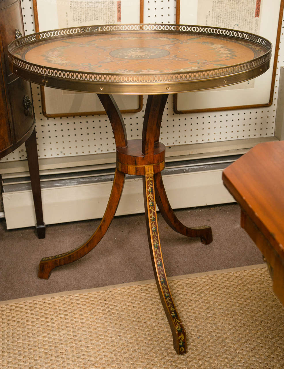 This table has a brass gallery surrounding the top. The background of the paint decoration of flowers, arabesques, and central musical instruments, is also faux bois paint. Each leg is similarly painted.
Under the top is the label for Chelsea