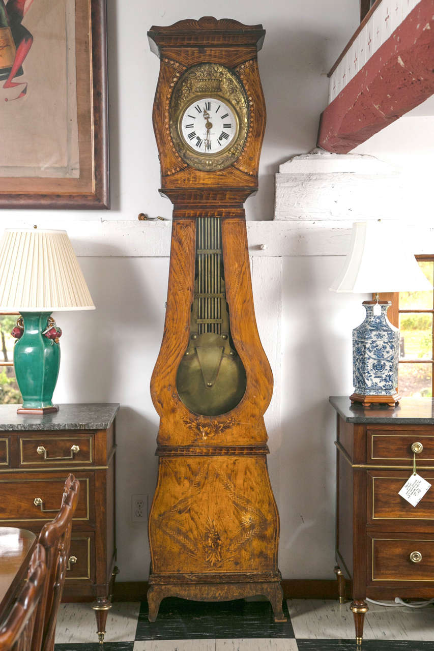 A painted case, enamel dial with brass surround and an elaborately decorated pendulum are the defining characteristics of a Morbier clock. At nearly eight feet tall, this is an imposing, yet charming tall case clock in classic high country style. PH
