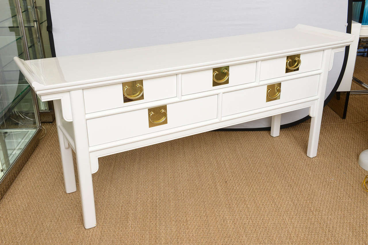 This simple and elegant white lacquered Hollywood Regency style cabinet / buffet / console for an entry hall / dining room has five drawers with beautiful original polished hardware. The two longer drawers are at the bottom.
Asian influences meets