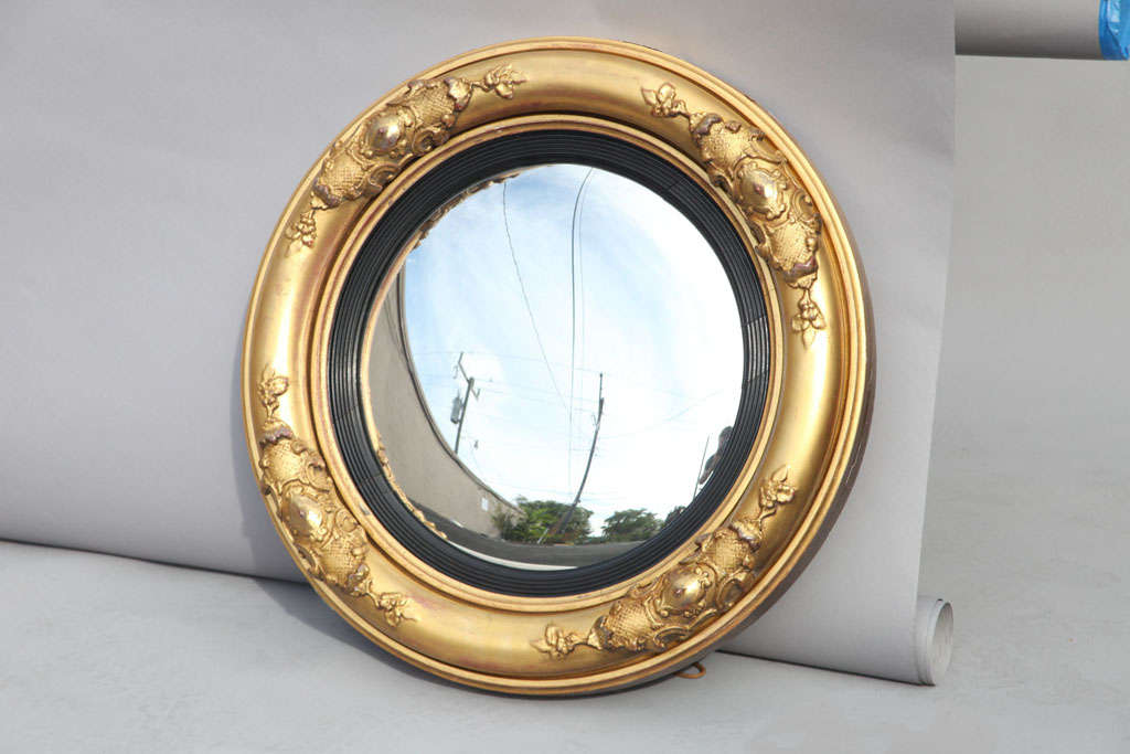 Period William IV bull's eye mirror, having a convex mirror with black reeded inner frame surrounded by molded giltwood decorated by four applied cartouches.
