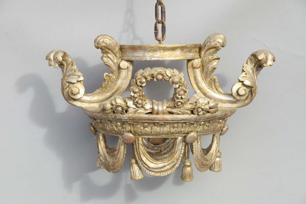 Bedsash crown (corona), of painted and gilded carved wood, with acanthus leaf scrolls, swags with tassels, and centered with a floral wreath; made to be lined with fabric and hung above a bed.
