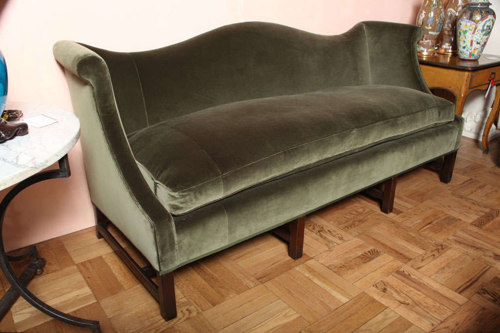 A Georgian Style Camelback Sofa with an exagerated and straight mahogany legs and stretcher