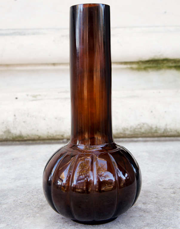 This simple form has been made in china from the early 18th century thru to the present day. This bottle form is a heavy long necked style which even today looks modern and chic. Blown from a rich brown glass the lobed lower section rests on a thick