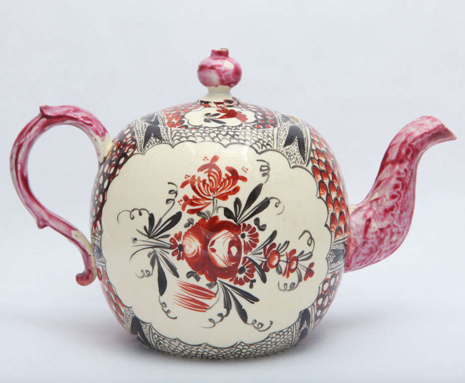 A rare English creamware teapot painted with chintz borders and King's Rose on the front and back