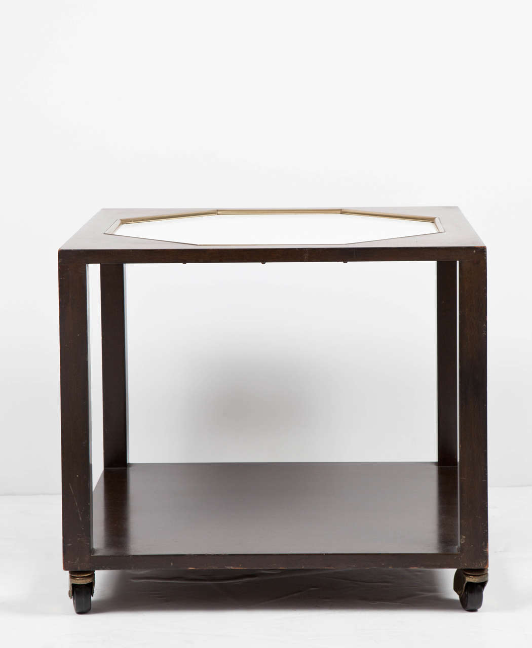 Walnut square-shaped end table with lower shelf, possibly by Harvey Probber. USA, circa 1960. Unsigned. Features a chocolate brown finish with white octagonal inset top with brass trim, complemented by removable casters.