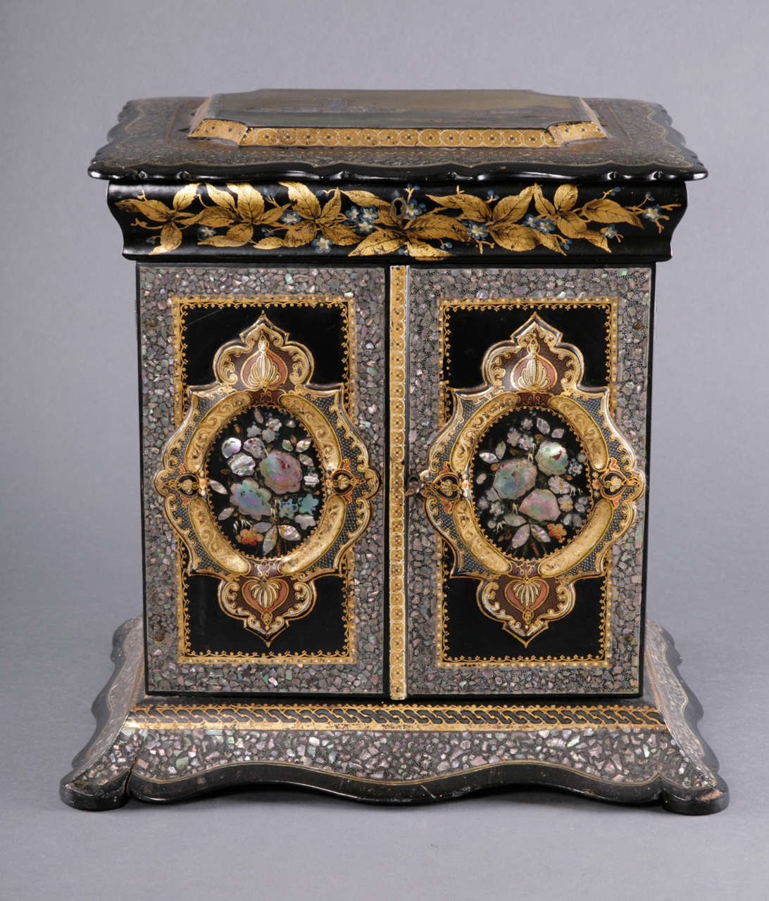 This large table cabinet is of exceptional quality and may have been made as an exhibition piece. The moulded lid of serpentine form incorporates a landscape scene inlaid with pieces of mother-of pearl. This lifts to reveal a workbox lined with