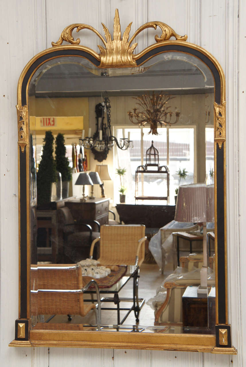 Black framed mantel pier mirror with gilt detailing, including sprays of leaves at top and sides.  Beveled glass.