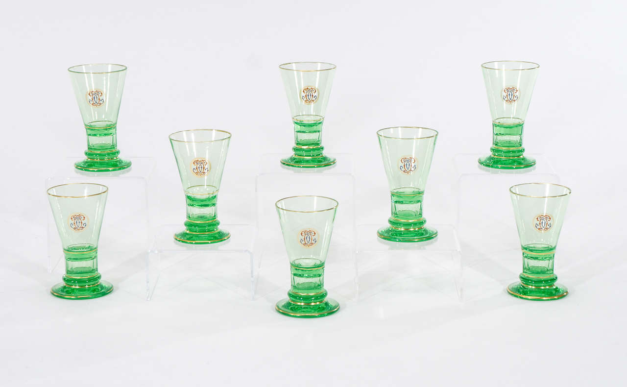 The lively color green of these handblown crystal goblets would set the tone of any cocktail party. They would also display well with the thick panel cut base and hand-painted enamel monograms and gold trim. Simple and elegant, these signed goblets