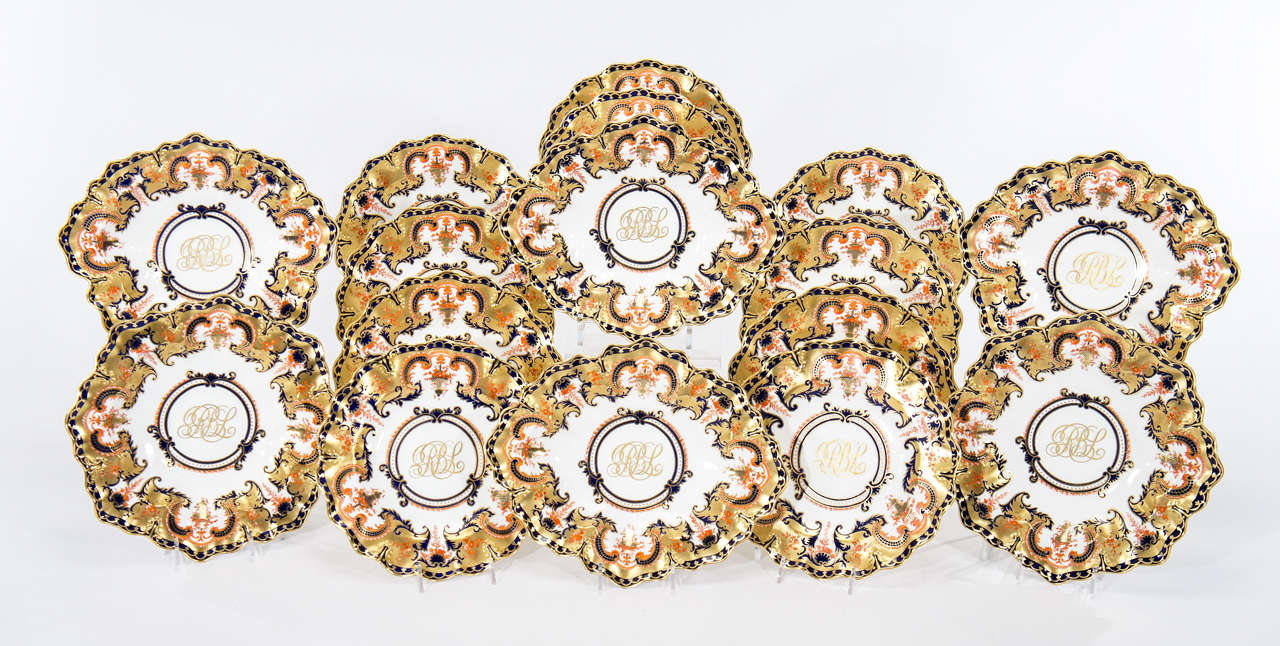 An unusually decorated custom ordered dessert service  embellished with an Art Nouveau style raised paste gold monogram on a undulating shaped rim plate. The set consists of 10 dessert plates 9.25