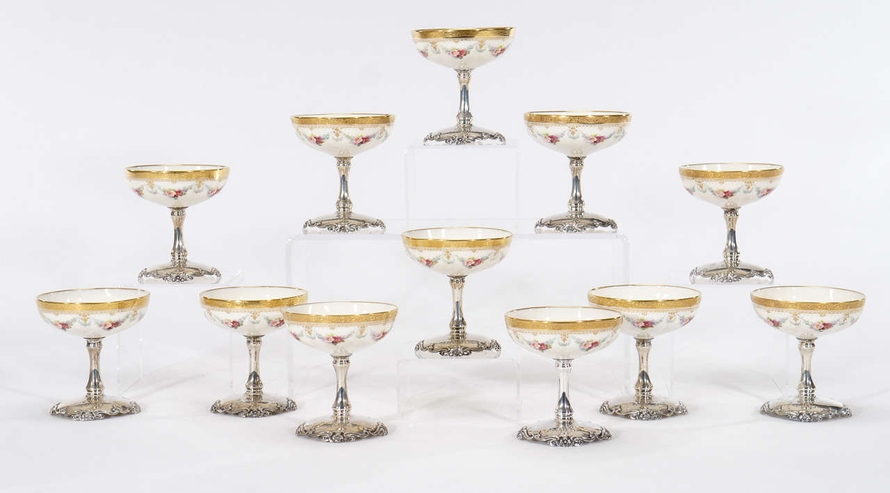 This is an unusual set of 12 dessert compotes/ sherbets with porcelain bowls and sterling silver stems and bases. The ornately decorated foot was custom-order and monogrammed for that client. The porcelain is beautifully hand painted with flowers