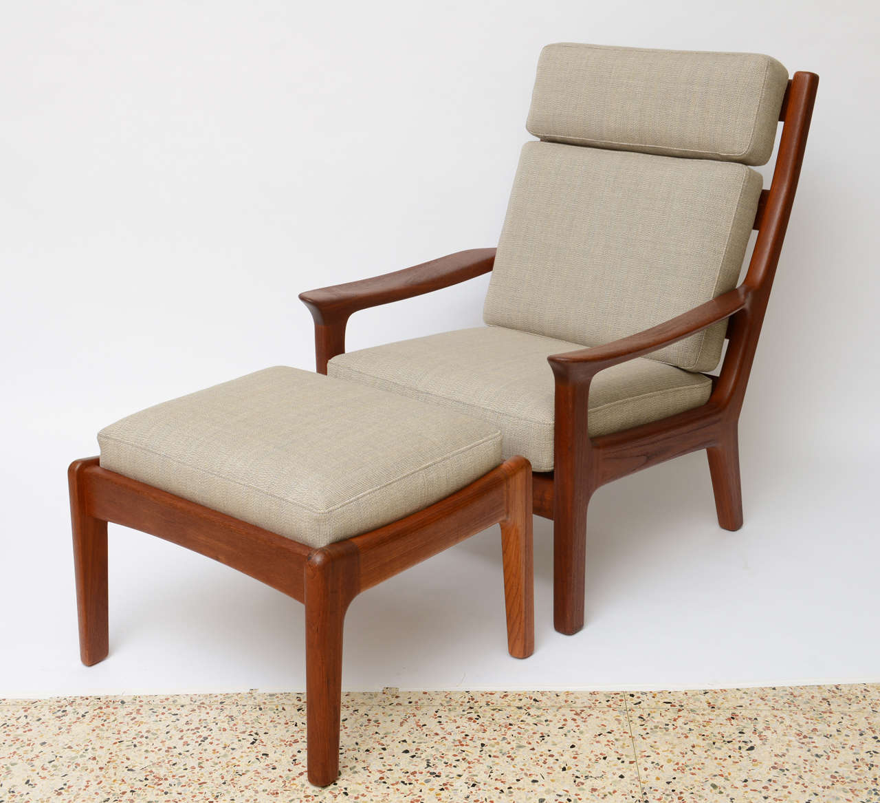 ....SOLD...Beautiful warm hand shaped solid teak highlights this very comfortable high back lounge chair and ottoman.  Made by Brdr Juul Kristensen in Denmark and attributed to Hans Olsen it features wide sculptured arms and lovely sloping profile. 
