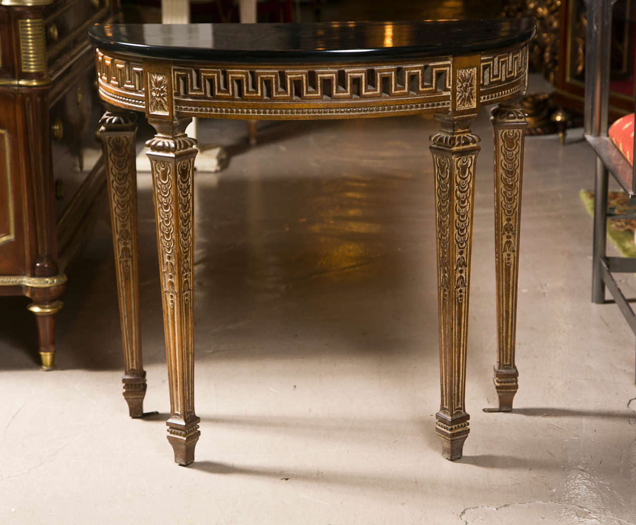 Pair of French Louis XVI style demilune console tables, circa 1940s, faux finished ebonized top over a narrow frieze with pierce-carved greey key motif, raised on four squared tapering legs ending in toupie feet.
