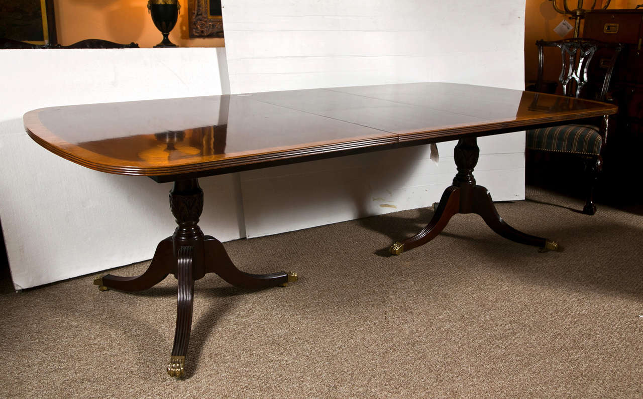 Banded mahogany 2-leaf dining table, custom quality by the Baker Furniture Company. Supported on a double pedestal extending to tripod legs ending in brass claw feet. 

Two Leaves: 20 inches depth by 46 inches width