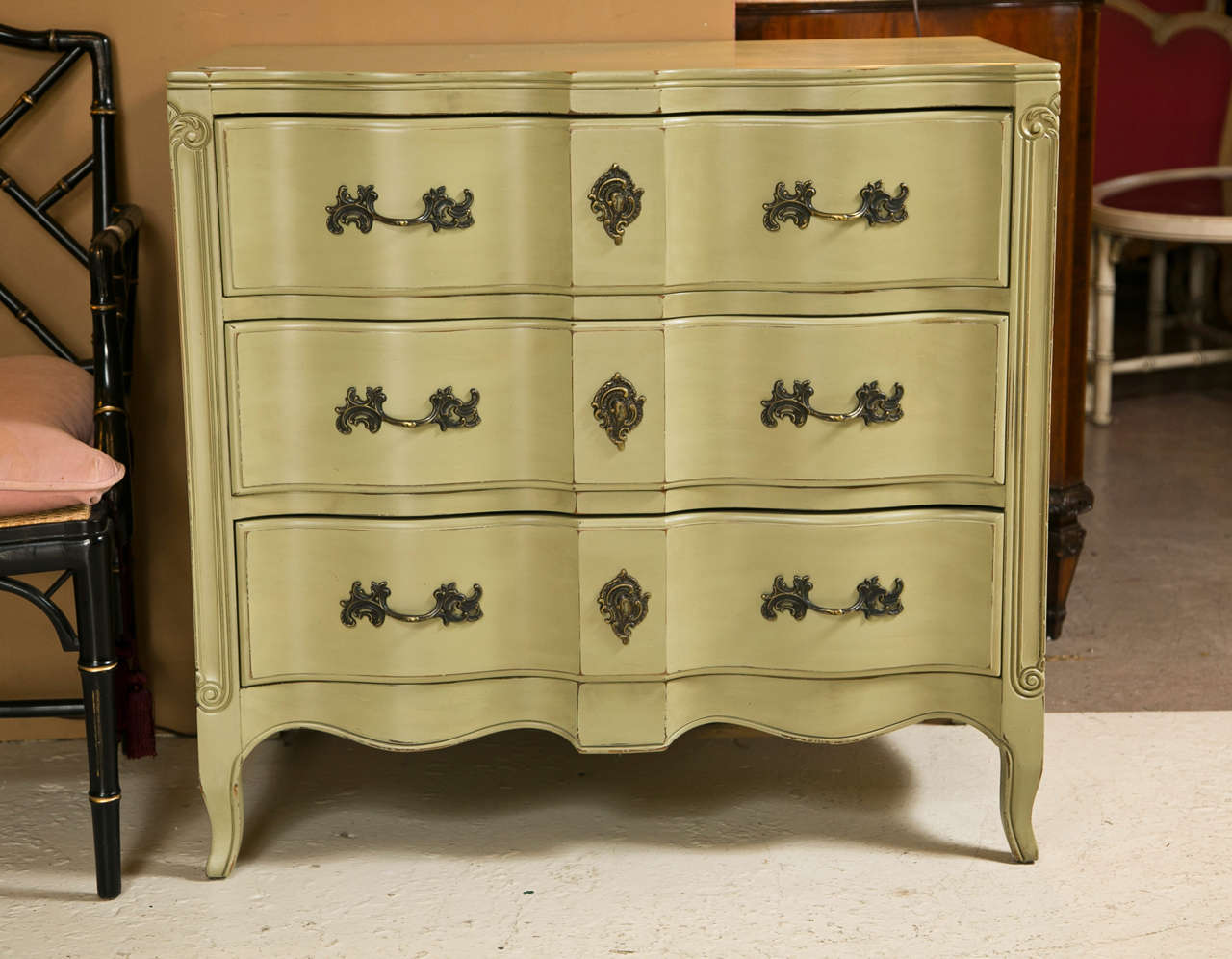 Pair of green painted French Provincial chests of drawers, each has a serpentine top, the enclosed case fitted with three drawers, raised on a scalloped apron and cabriole legs.