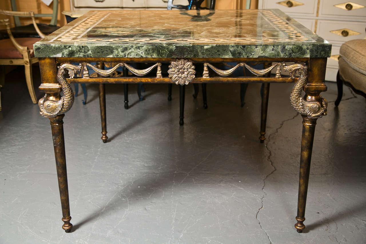 A center table by Maitland-Smith, the green granite top with wavy inlaid, atop a gilt-metal base with the beautiful flower, drapery, and dolphin motifs.