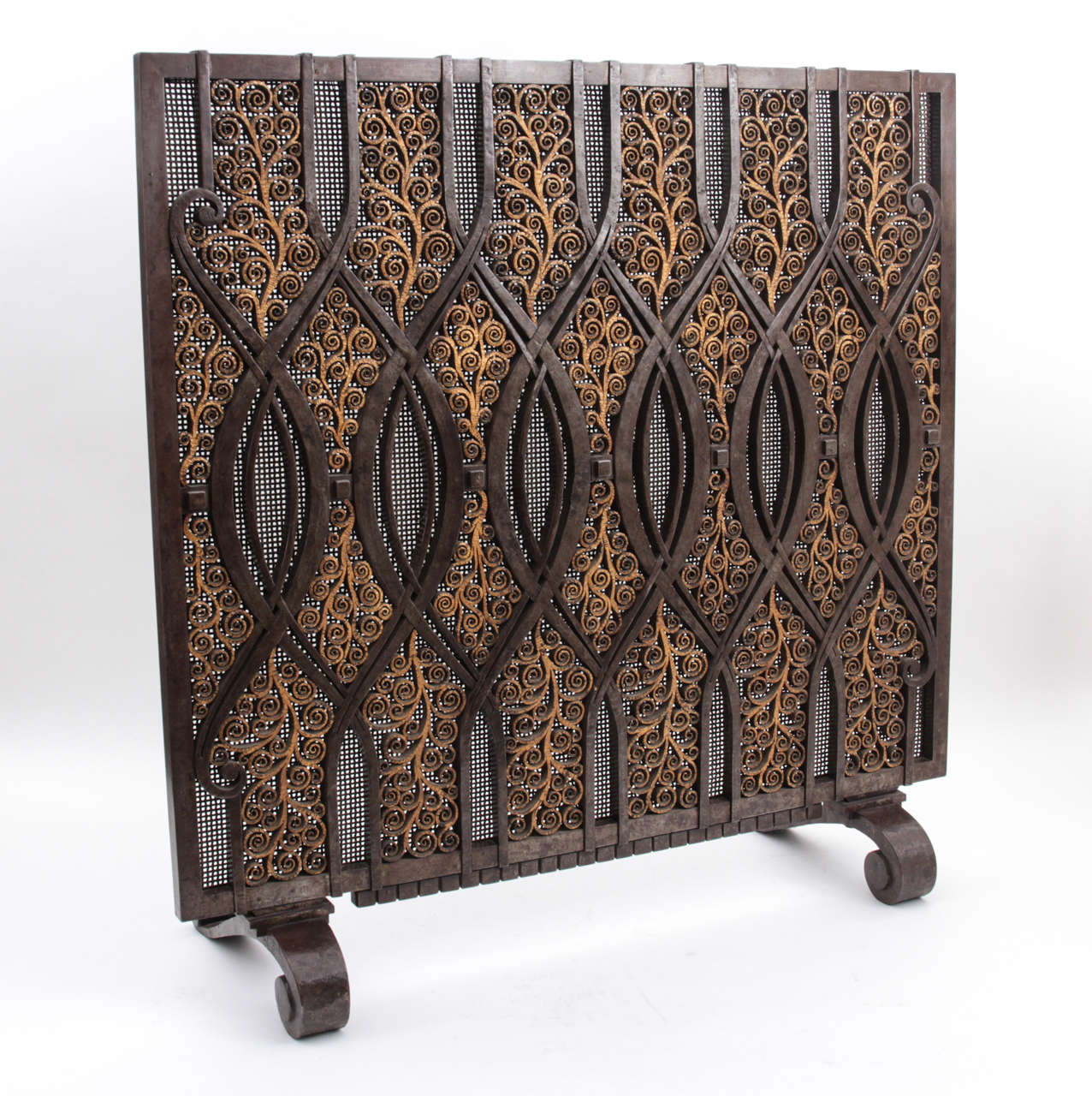 EDGAR BRANDT  (1880-1960)  France

Fire screen c. 1925

Patinated wrought-iron with a bronze tone and a delicately wrought gilt iron scrolling vine motif with intersecting elliptical center medallions, all backed with a finely woven iron screen,