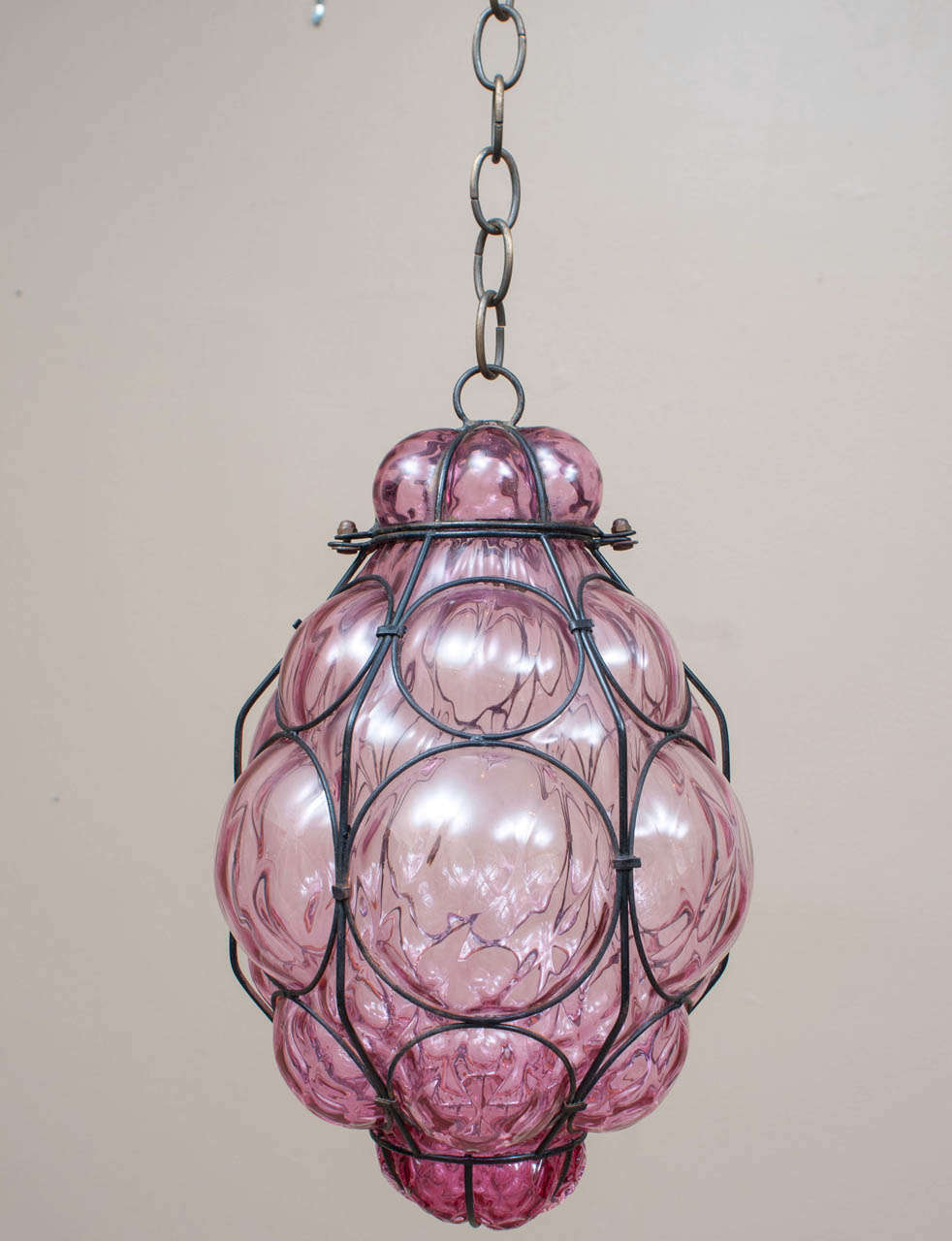 The pale wine-colored Venetian glass on this lantern was hand-blown in a mold and the wire skeleton was then hand-applied to the glass - the metal has nice evidence of age which gives the lantern a beautiful patina - 3 lights - comes apart for bulb