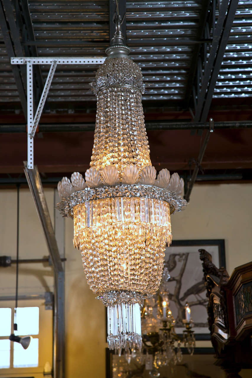 This all original chandelier has many facets of crystal design.Comes from either a theatre or opera house.  It captures all the characteristics of glamour and charm from years ago.  It has long slender pointed prisms on both the upper/lower parts of