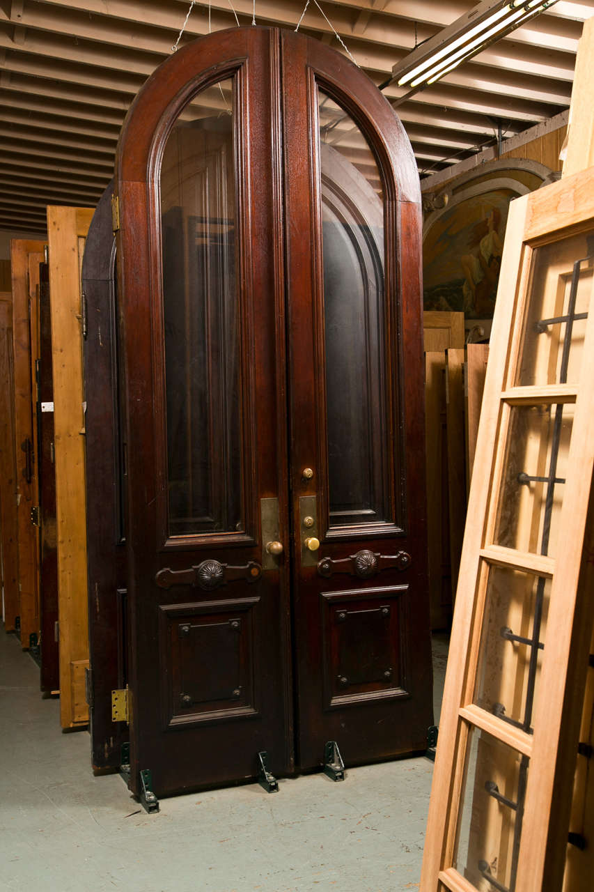 Antique Arched Pair of Walnut entry doors with glass panels.  Beautiful set which were salvaged from a New York City upper east side home.  This pair truly makes for a super entry.  Doors are heavy....2 3/4