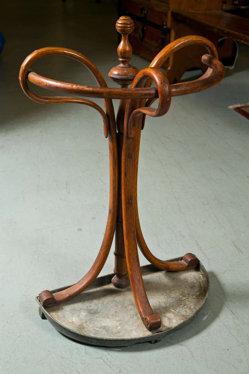 A bentwood umbrella stand. By Thonet, designed in 1888, executed 1888-1911.  The top consisting of three elaborately curved legs on a demi-lune shaped zinc base.