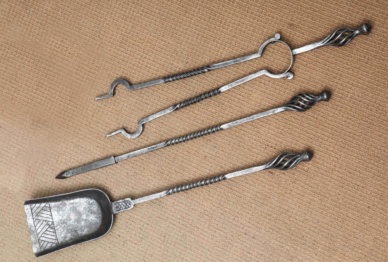 Set of three English Arts and Crafts steel fire tools, the handles with open spirals over square shafts having barley twist cnters, the solid shovel with etched decoration.