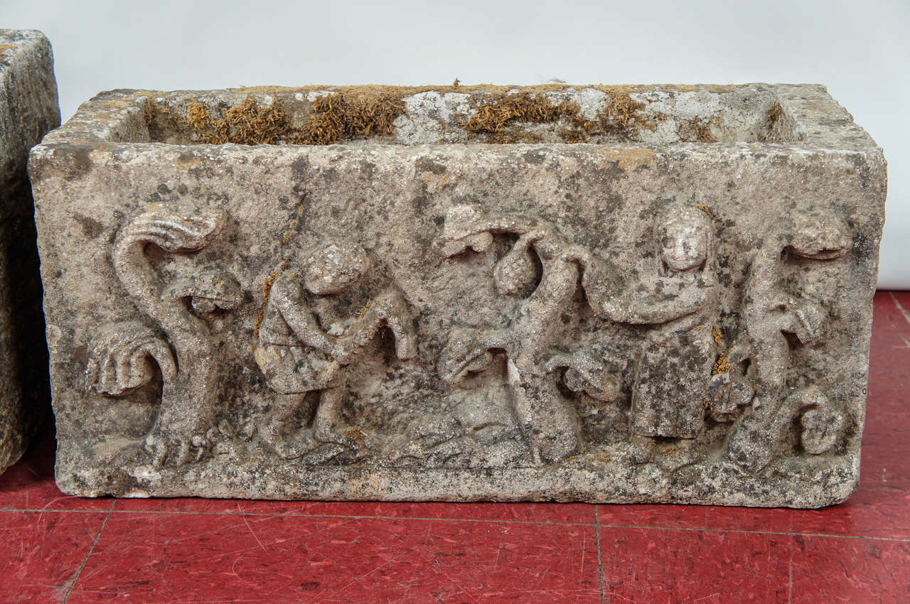 Medieval planter has sculpted stone figures en relief depicting serpents and human figures. Possibly based on Biblical stories.  The scene is only on one side with three sides plain.

Measurements for smaller planter: 7.25