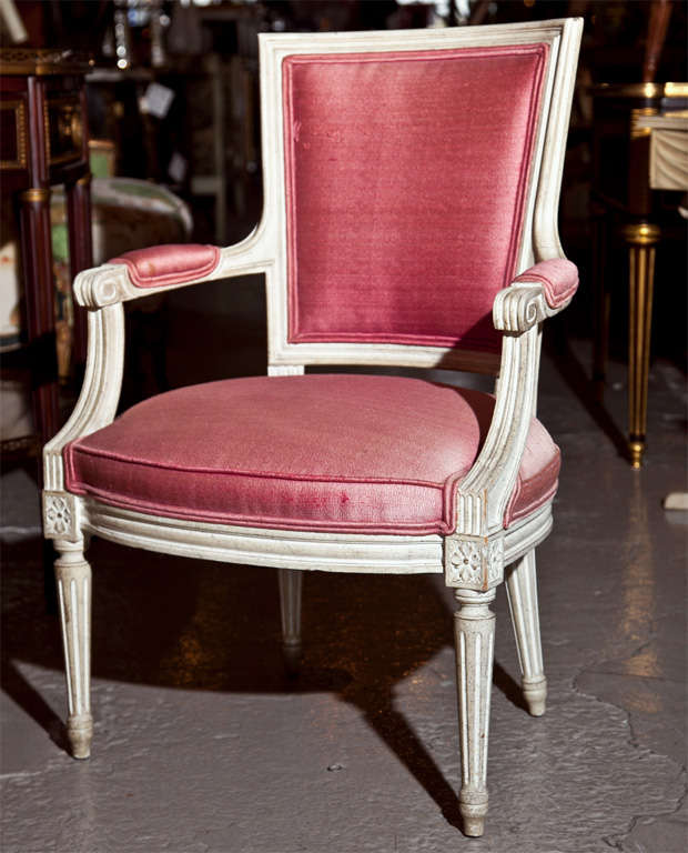 Pair of French Louis XVI style white distress painted fauteuils, circa 1940s, squared back padded with pink linen, padded arm rests and seat, raised on tapering fluted legs. By Maison Jansen.