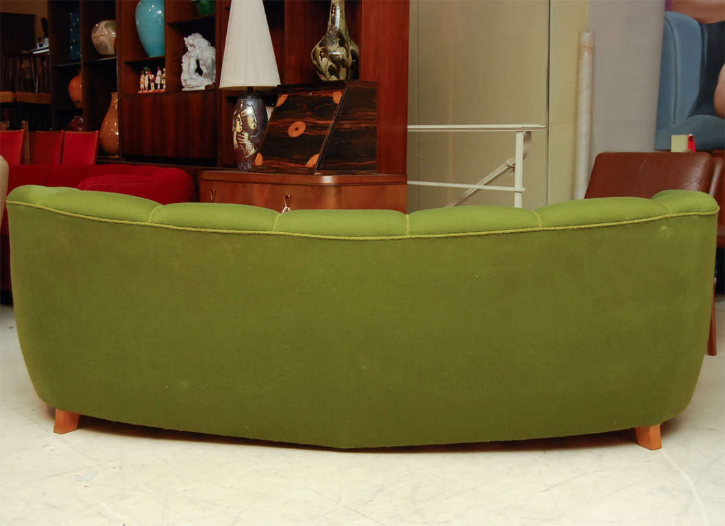 Curved 'banana' sofa in green with channelled upolstery and birchwood feet