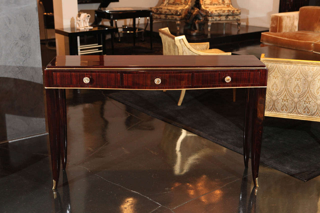 An elegant console in rosewood veneer and brass hardware and gilded details. Signed by Albert Fournier and Company with original metal plate, from France 1940. Thee drawers on front side for light storage.