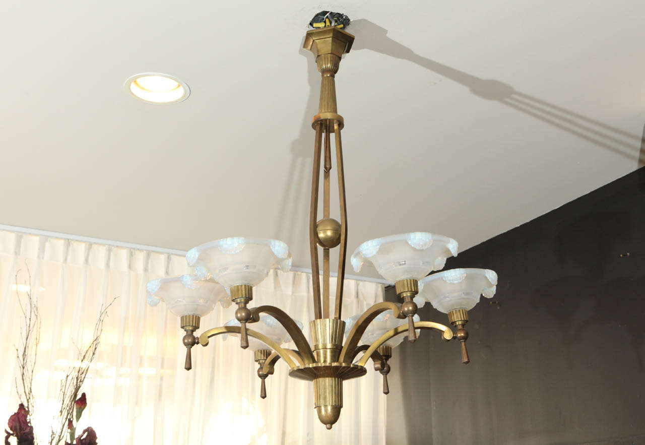 This French Art Deco chandelier by Petitot features six original waterfall opaline glass shades on antique brass. The design combines a modernistic frame with ornamental shades. Signed.