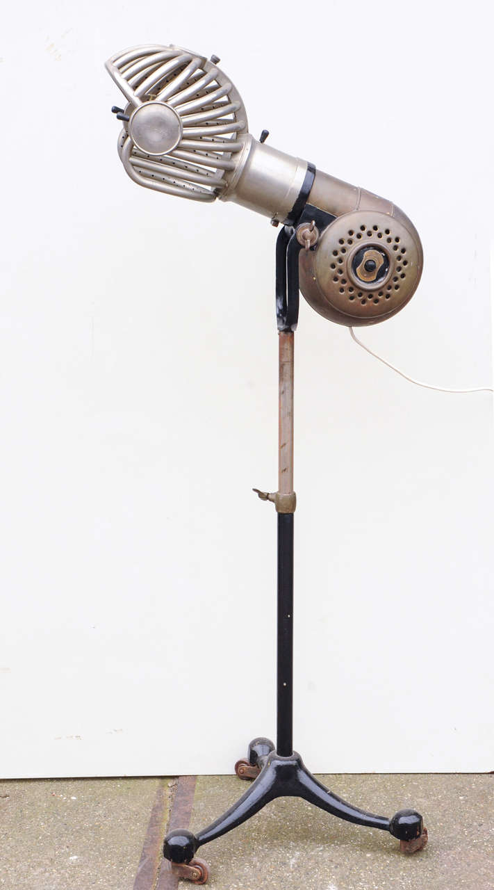 A freaky looking barbers hair dryer, steampunk/rough luxe style on cast iron tripod. The fan/motorpart shaped as a copper nautilus shell. The head part shaped as a futuristic nickel plated helmet. The heater and the fan in good working order, 220 V.