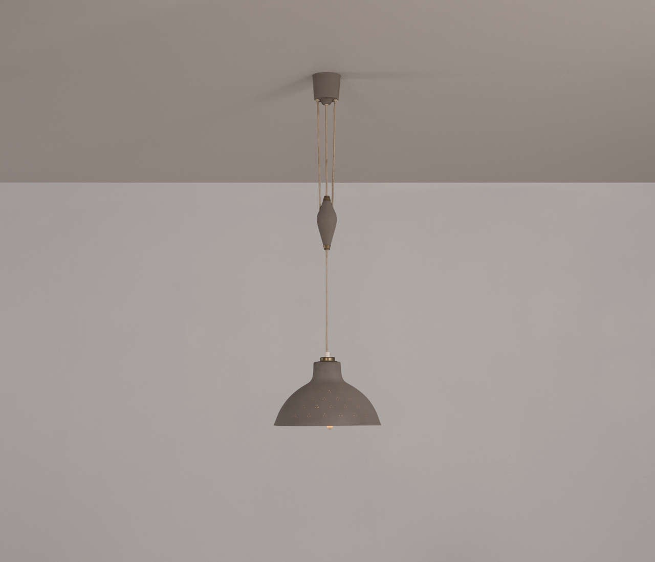 Very elegant shaped pendant with a perforated shade, finished with subtle solid brass details in the style of Paavo Tynell.

This very well made piece is equipped with a narrow infundibular shaped end which leads the wire to a return on the