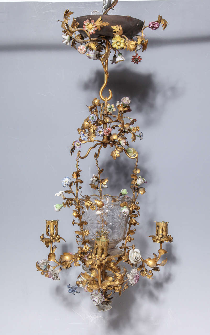 Louis XVI French hand cut-glass and doré bronze four-light chandelier or lantern with porcelain flowers. The bronze is shaped into life like vines and leaves while each porcelain flower is hand-painted with a myriad of colors. The original glass is